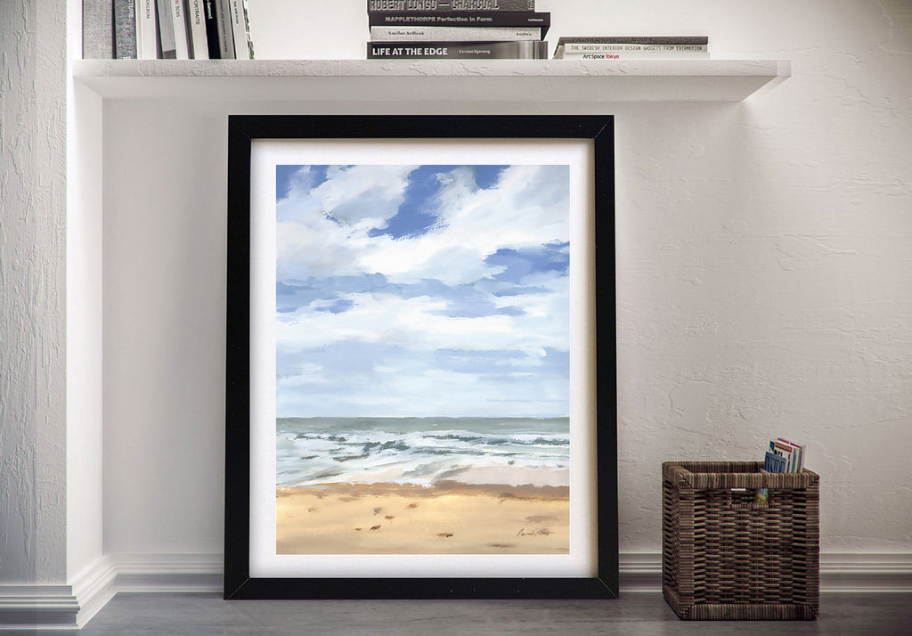 Framed beach print on a wall next to a shelf with books and a basket.